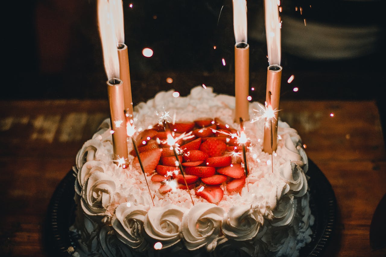 ours-journey Celebrate with a festive strawberry-topped birthday cake adorned with sparkler candles, creating a joyful atmosphere.