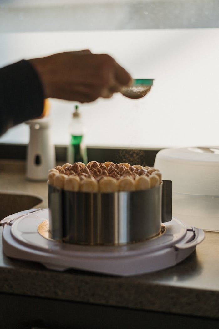 Artistic shot capturing the delicate process of assembling a layered mascarpone cake in a cozy kitchen.